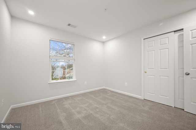 unfurnished bedroom featuring light colored carpet and a closet