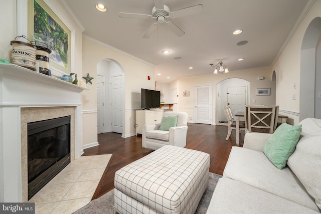 living room with ceiling fan, a fireplace, hardwood / wood-style floors, and ornamental molding