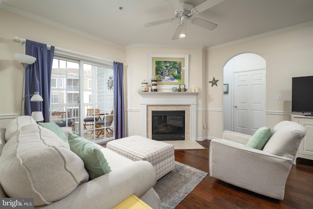 living room with a tile fireplace, dark hardwood / wood-style flooring, ceiling fan, and crown molding