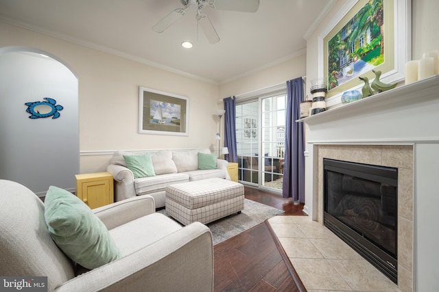 living room featuring crown molding, a fireplace, ceiling fan, and light hardwood / wood-style floors