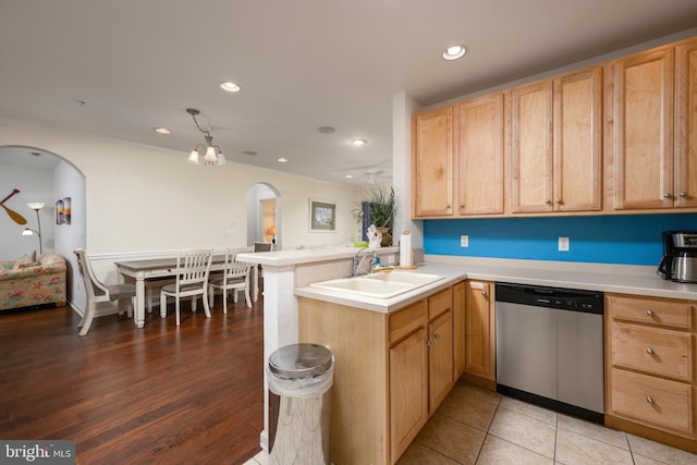 kitchen featuring kitchen peninsula, light brown cabinetry, stainless steel dishwasher, and sink