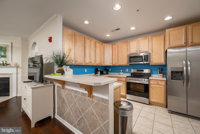 kitchen with crown molding, light brown cabinets, light tile patterned floors, and stainless steel appliances