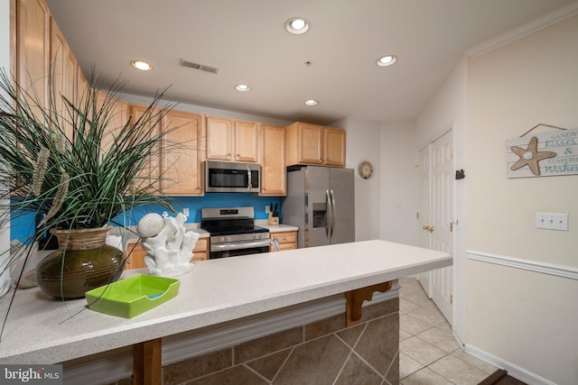 kitchen with crown molding, light brown cabinets, light tile patterned floors, and stainless steel appliances