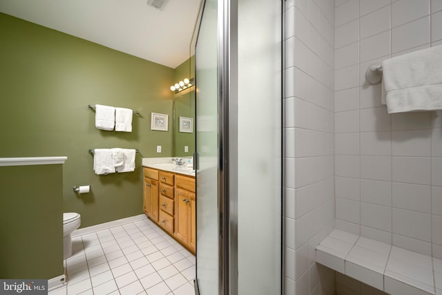 bathroom with tile patterned floors, vanity, tiled shower, and toilet