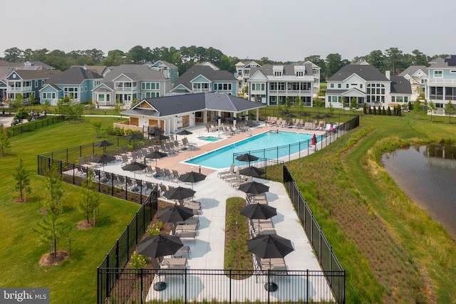 view of swimming pool with a patio area, a yard, and a water view