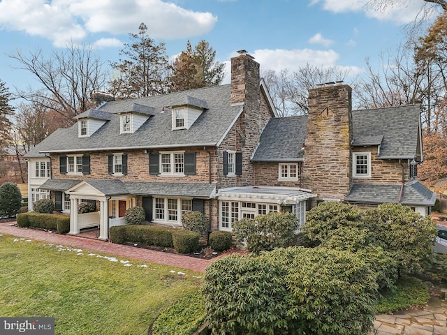 view of front of house featuring roof with shingles, a chimney, and a front yard