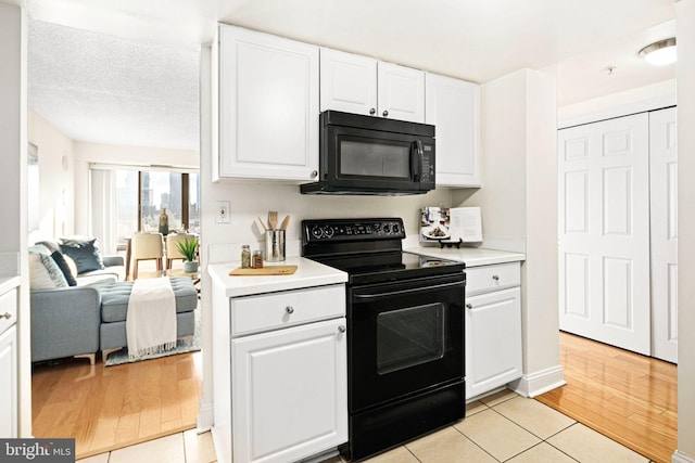 kitchen featuring white cabinetry, light tile patterned floors, black appliances, and a textured ceiling