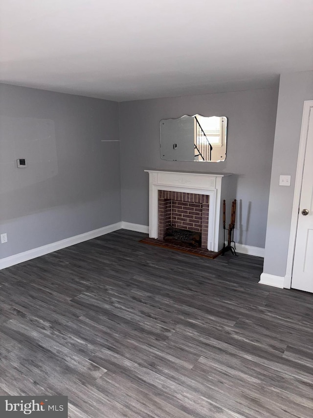 unfurnished living room featuring dark hardwood / wood-style floors and a brick fireplace