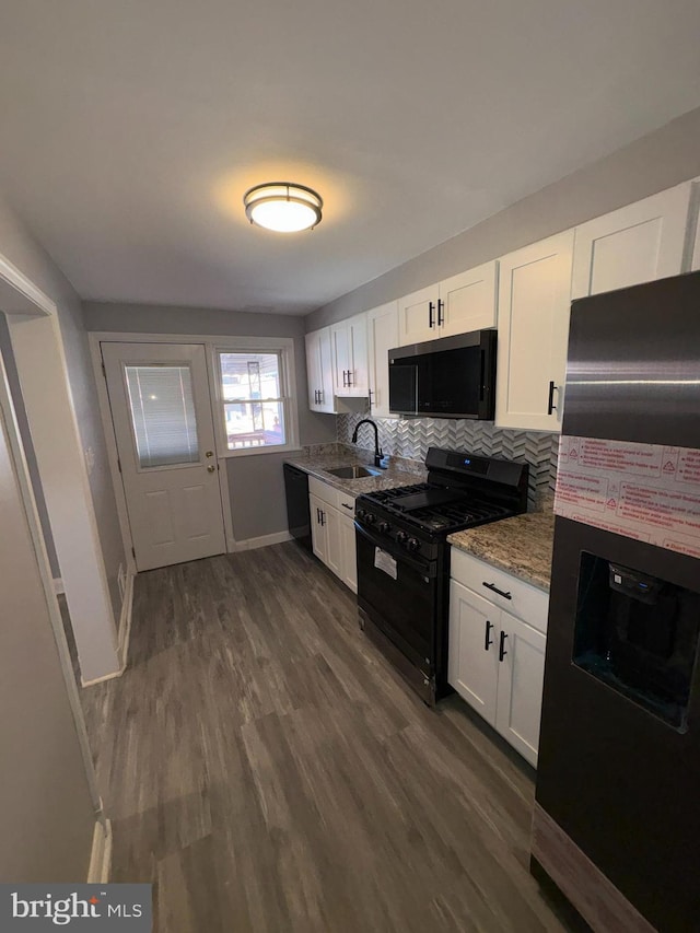 kitchen featuring sink, light stone counters, white cabinetry, and black appliances