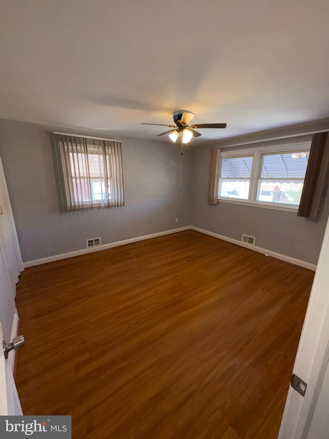 empty room with ceiling fan and dark hardwood / wood-style flooring