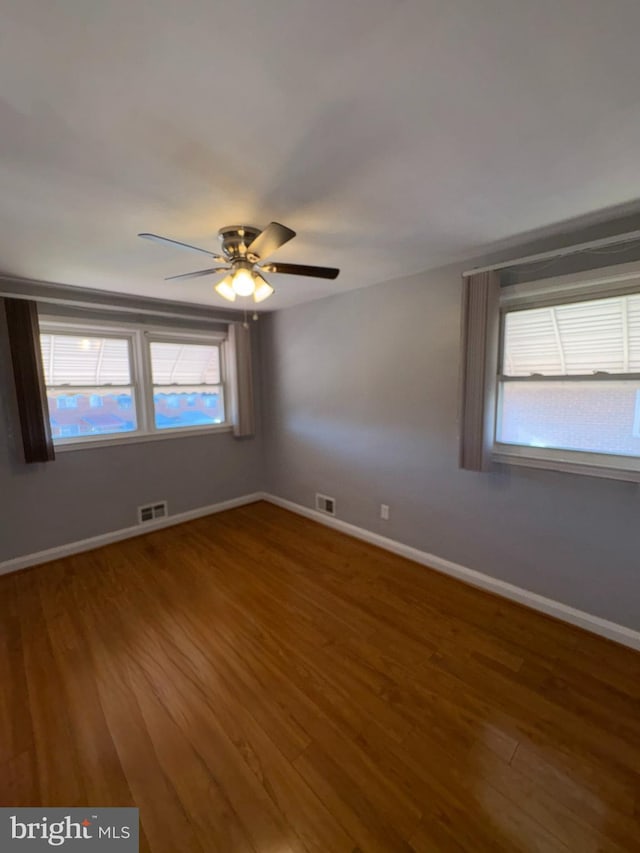 unfurnished room with hardwood / wood-style flooring, ceiling fan, and a healthy amount of sunlight