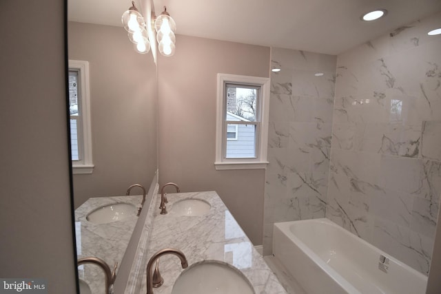 bathroom with vanity, tiled shower / bath, and a notable chandelier