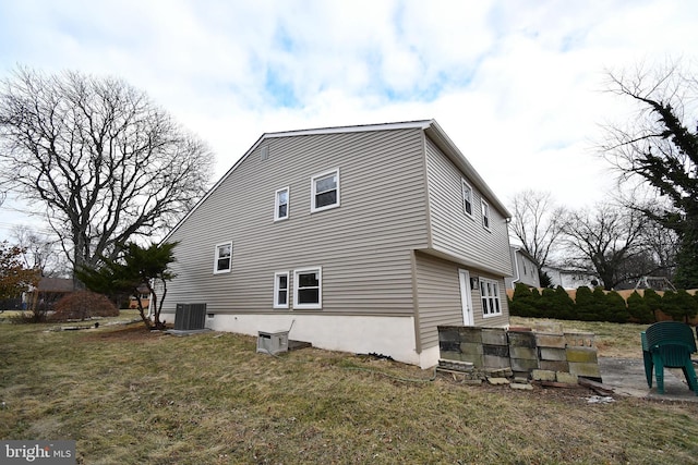 view of side of property featuring central AC and a lawn