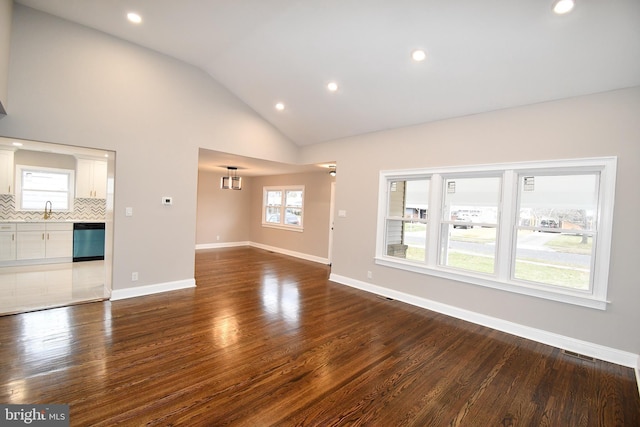 unfurnished living room with sink, high vaulted ceiling, and dark wood-type flooring