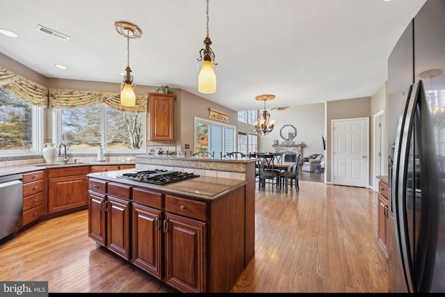 kitchen with gas cooktop, black fridge, dishwasher, hanging light fixtures, and sink