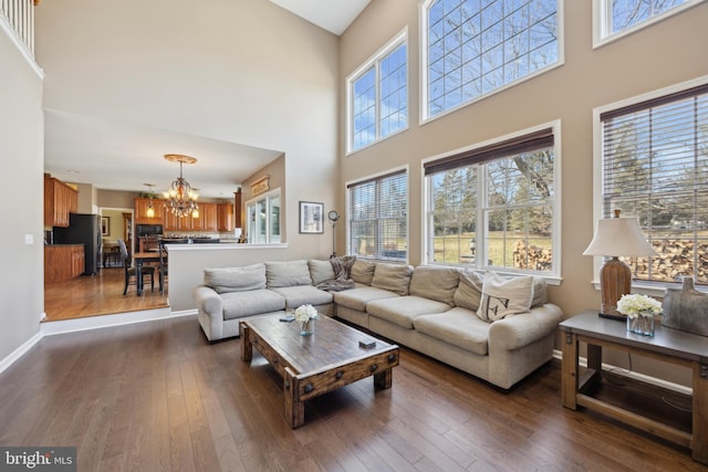 living room featuring dark hardwood / wood-style flooring, a towering ceiling, and a notable chandelier