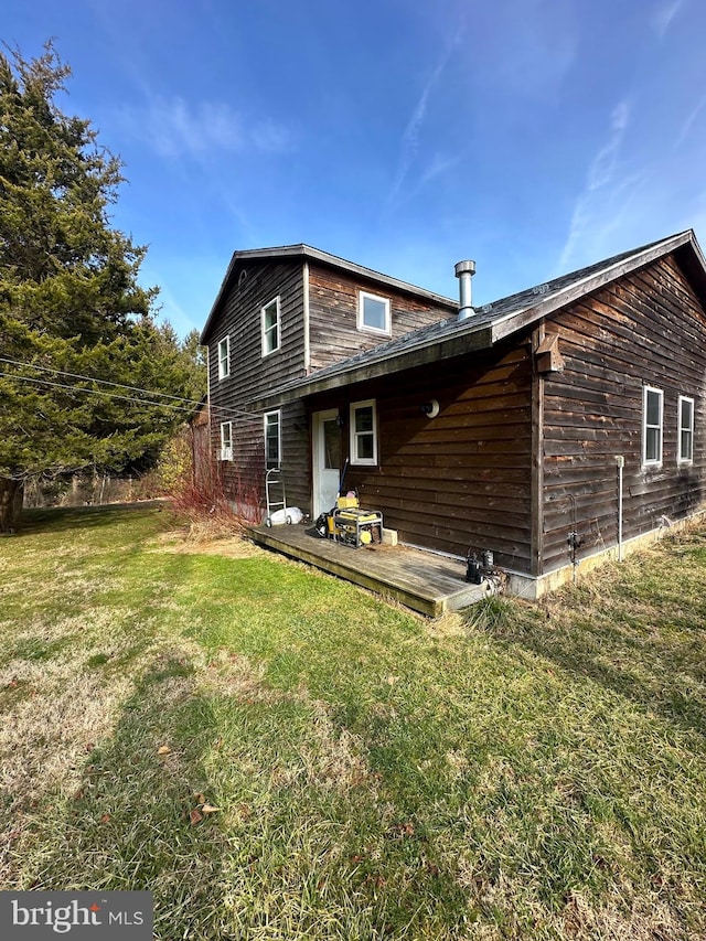 back of property with a wooden deck and a lawn