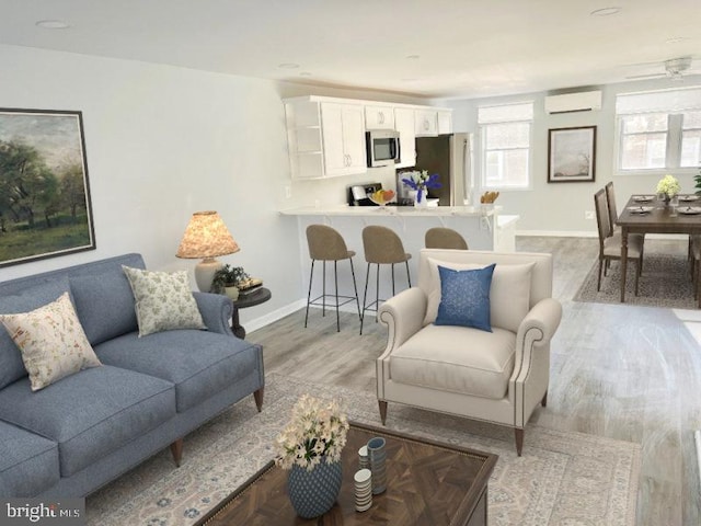 living room with a wall mounted air conditioner and light wood-type flooring