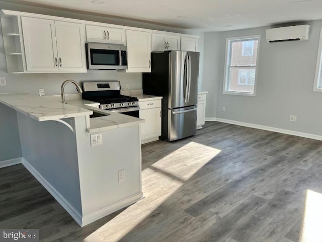 kitchen with a breakfast bar, white cabinets, appliances with stainless steel finishes, kitchen peninsula, and a wall unit AC