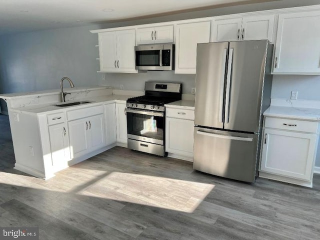 kitchen featuring kitchen peninsula, stainless steel appliances, white cabinetry, and sink