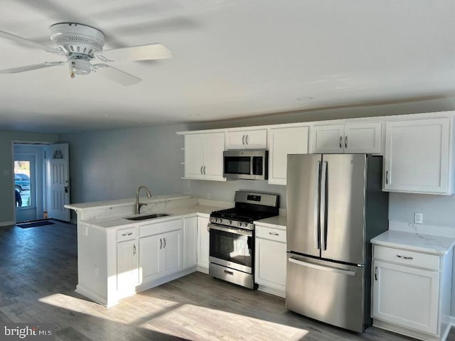 kitchen with kitchen peninsula, stainless steel appliances, white cabinetry, and sink