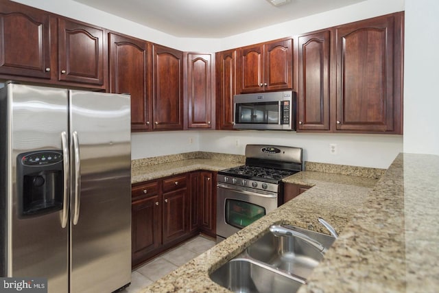 kitchen with light stone countertops, light tile patterned floors, stainless steel appliances, and sink