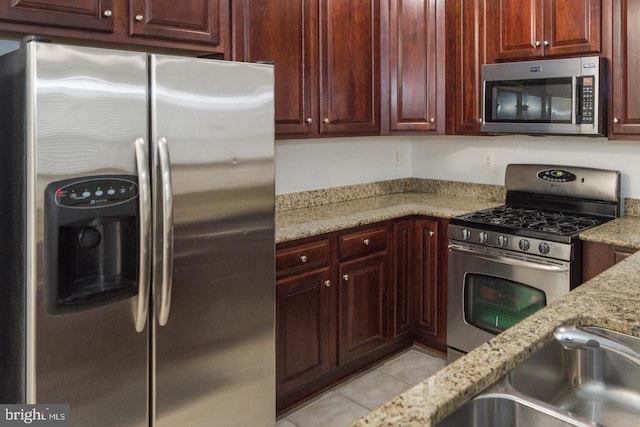 kitchen featuring light stone countertops, light tile patterned flooring, and stainless steel appliances