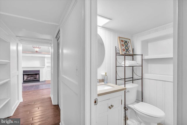 bathroom with hardwood / wood-style floors, vanity, ornamental molding, and toilet