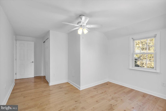 empty room with ceiling fan, vaulted ceiling, and light hardwood / wood-style flooring