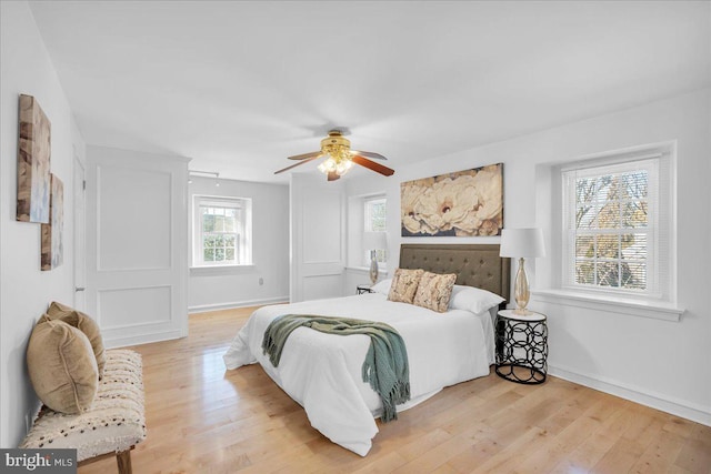 bedroom with ceiling fan, light hardwood / wood-style floors, and multiple windows