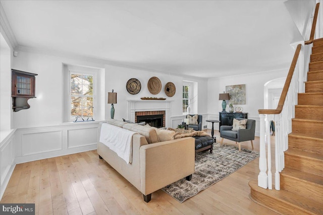 living room with light hardwood / wood-style flooring, a brick fireplace, a healthy amount of sunlight, and crown molding