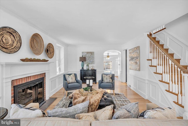 living room featuring ceiling fan, plenty of natural light, light wood-type flooring, and a brick fireplace