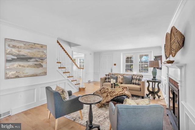 living room with light wood-type flooring, plenty of natural light, and ornamental molding