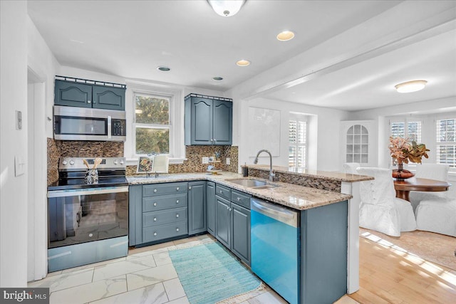 kitchen with tasteful backsplash, kitchen peninsula, sink, and stainless steel appliances