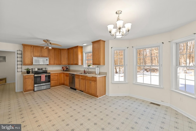 kitchen featuring ceiling fan with notable chandelier, sink, stainless steel appliances, and hanging light fixtures