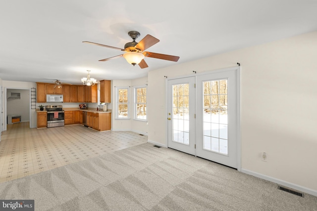 unfurnished living room with light carpet, sink, and ceiling fan with notable chandelier