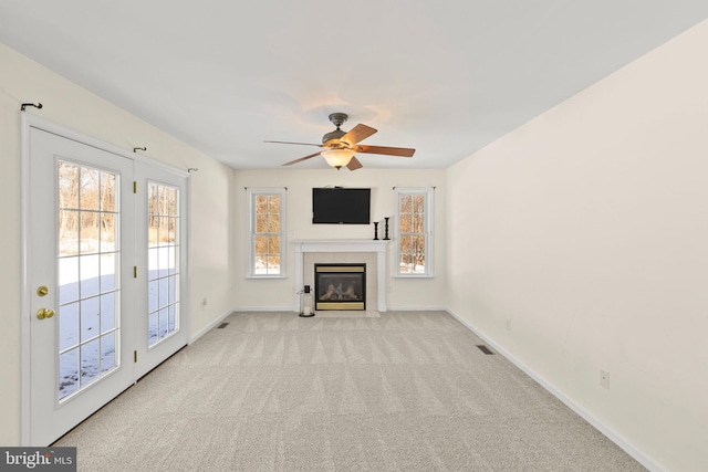 unfurnished living room featuring ceiling fan, light colored carpet, and a tile fireplace