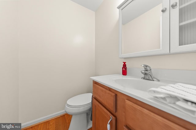 bathroom with wood-type flooring, vanity, and toilet