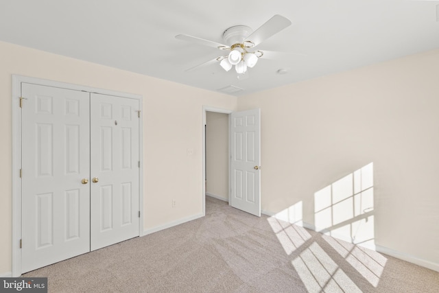 unfurnished bedroom featuring ceiling fan, light colored carpet, and a closet