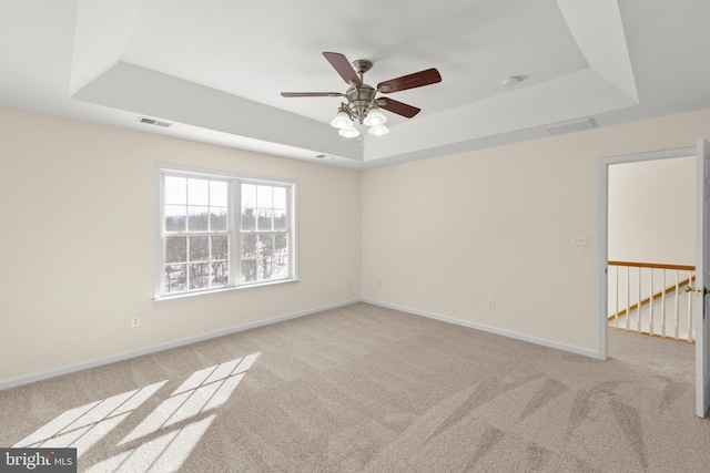 carpeted spare room featuring ceiling fan and a tray ceiling