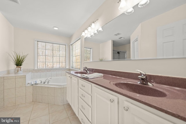 bathroom with tile patterned flooring, vanity, and tiled tub