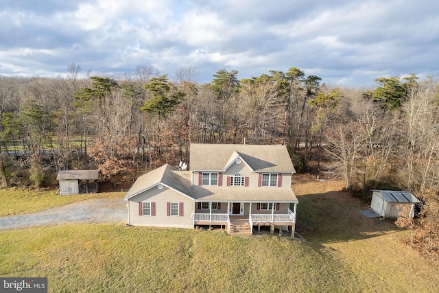 view of front of home with covered porch, a storage shed, and a front lawn