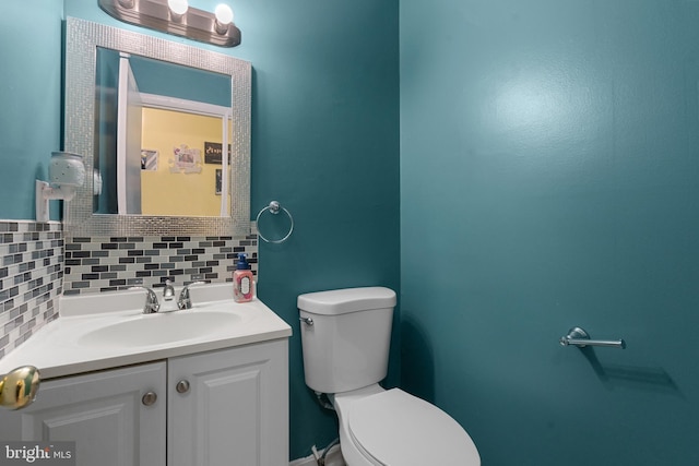 bathroom featuring vanity, toilet, and tasteful backsplash