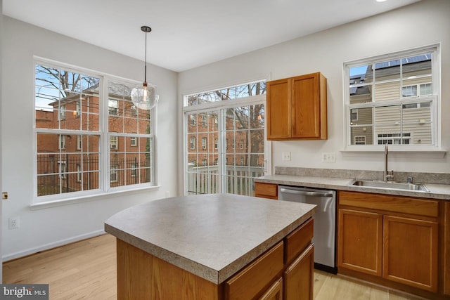 kitchen featuring a center island, sink, hanging light fixtures, stainless steel dishwasher, and light hardwood / wood-style floors