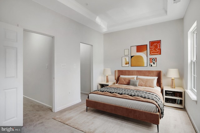 bedroom with light carpet and a tray ceiling