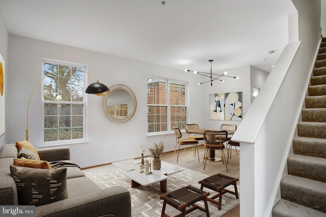 living room featuring light wood-type flooring, plenty of natural light, and a notable chandelier