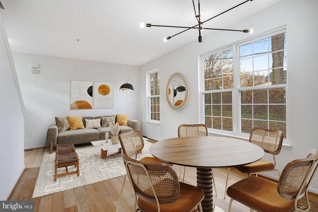 dining area with light wood-type flooring and a notable chandelier