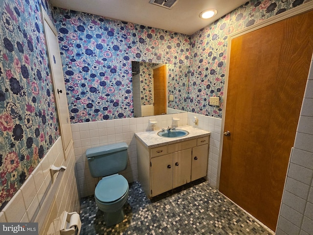 bathroom featuring tile patterned floors, vanity, tile walls, and toilet