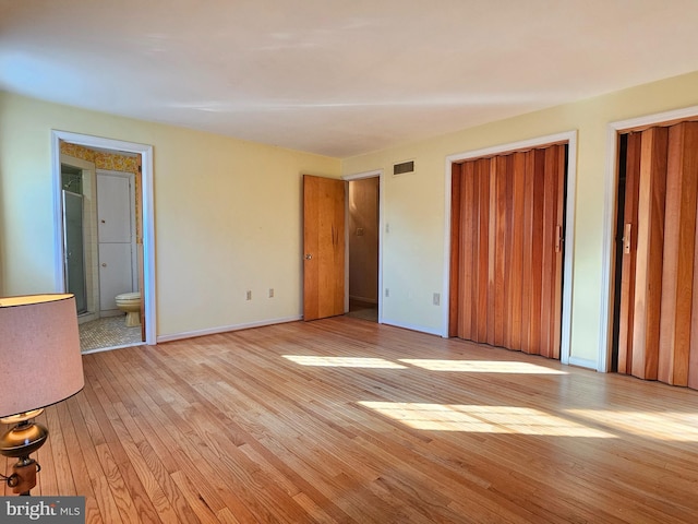 unfurnished bedroom featuring light wood-type flooring, connected bathroom, and a closet