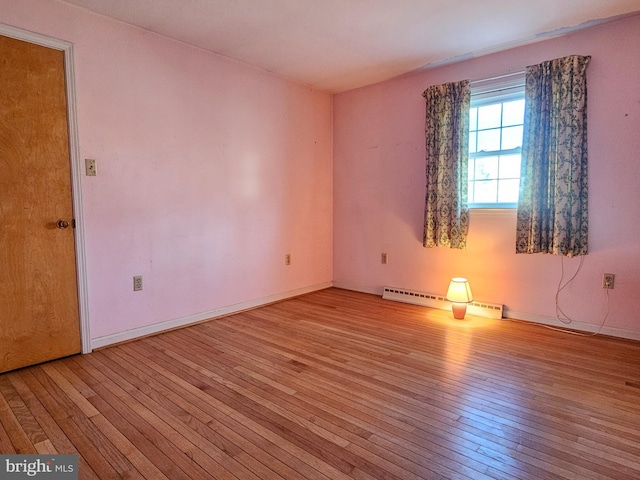 unfurnished room with light hardwood / wood-style flooring and a baseboard heating unit